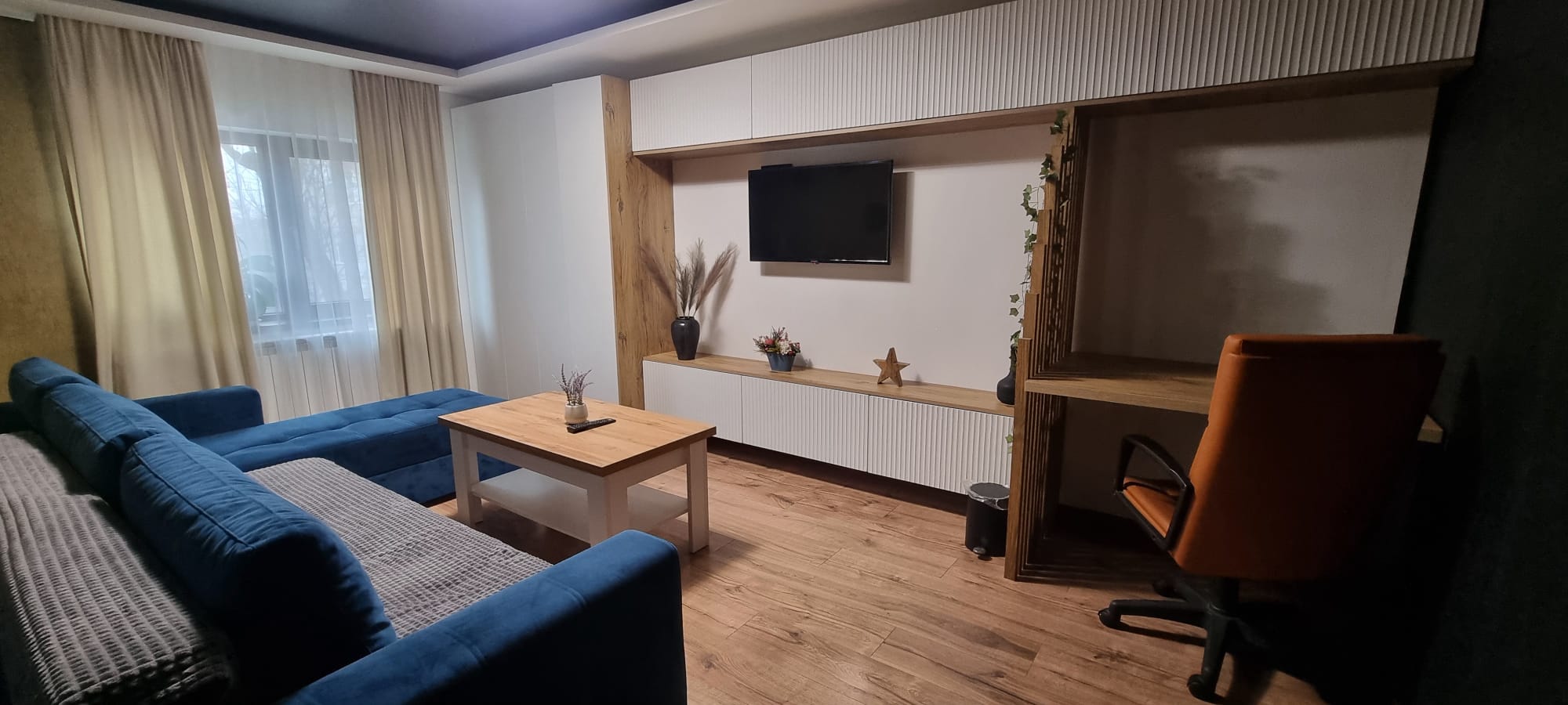 Living cu canapea albastră și colț de birou